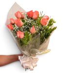Buquê de rosas corais com chuva de prata, folhagens e laço claro