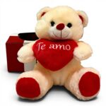 Urso de pelúcia creme segurando coração vermelho escrito Te amo